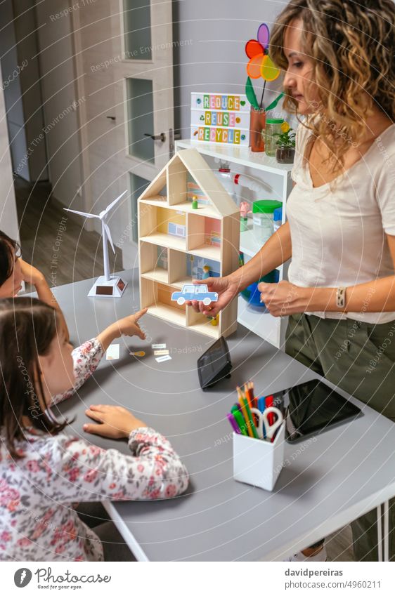 Lehrerin erklärt ihren Schülern die Bestandteile eines nachhaltigen Hauses und zeigt ein Elektroauto Ökologie Klassenraum zu erklären. zeigend