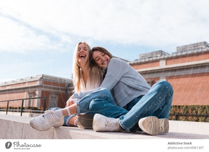 Positive Frauen, die sich in der Stadt umarmen und in die Kamera schauen Umarmung Freund bester Freund Freundschaft Lächeln kuscheln Großstadt Wochenende