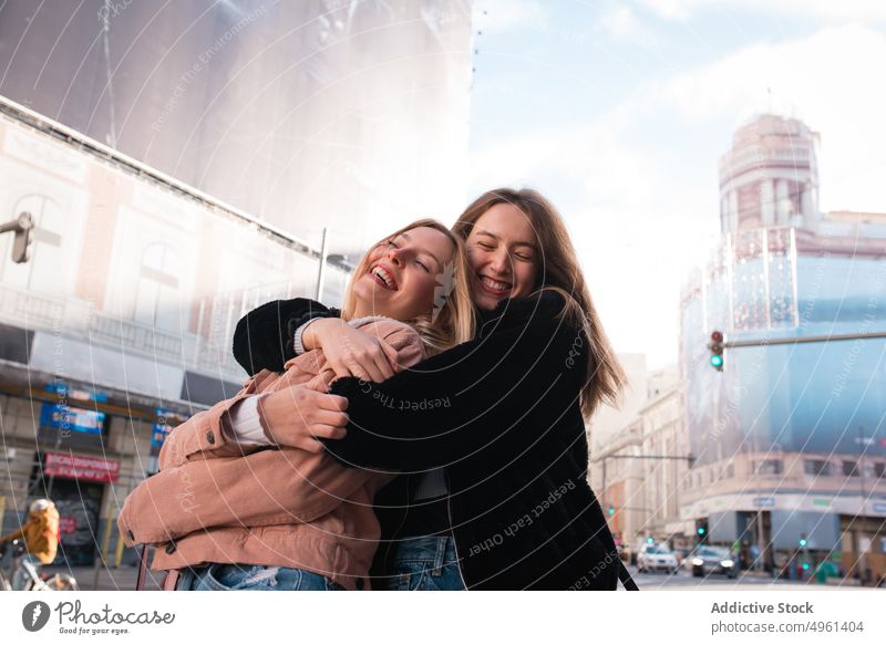 Glückliche Frauen, die sich bei einem Stadtbummel auf der Straße umarmen Freund Umarmung Freundschaft bester Freund Umarmen heiter Großstadt Spaß haben genießen