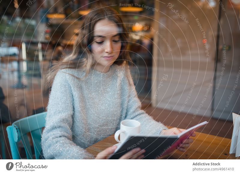 Junge Frau liest Buch im Café lesen heiter interessant Literatur genießen Leseratte Kantine Lächeln Lifestyle sitzen Freude ruhen sich[Akk] entspannen Tisch