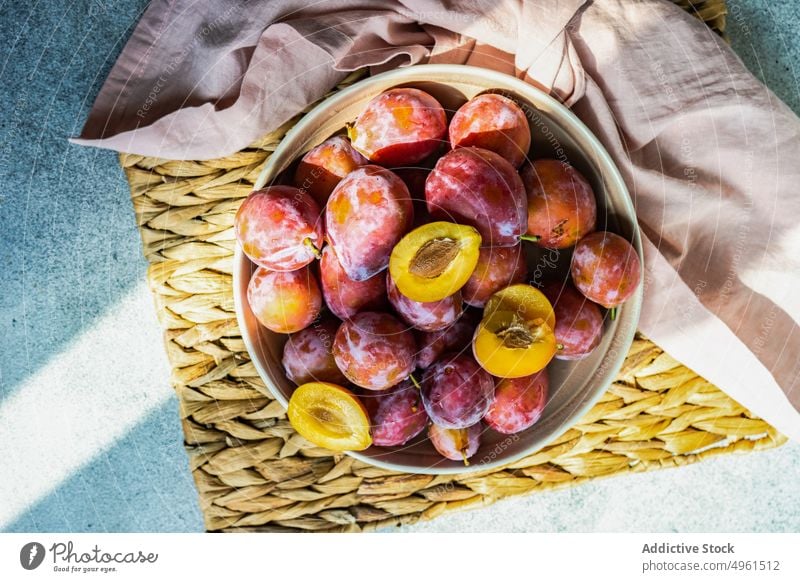 Reife Bio-Pflaumen in der Schale Schalen & Schüsseln Keramik Dessert essen Lebensmittel frisch Frucht Ernte Gesundheit organisch rosa Unterlage Pflanzenbasiert