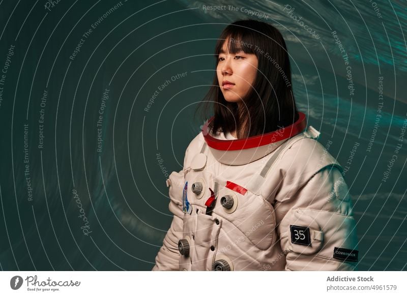 Ruhiger asiatischer Kosmonaut schaut weg Frau bereit Missionsstation Windstille ernst Raumanzug futuristisch modern jung Chinesisch Japanisch ethnisch