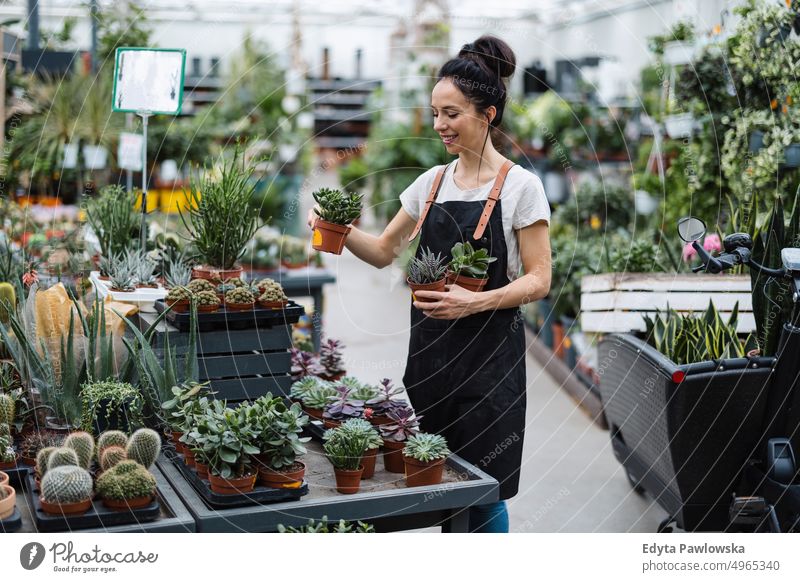 Aufnahme einer jungen Frau bei der Arbeit mit Pflanzen in einem Gartencenter Gärtnerei Lächeln Positivität Natur Gartenarbeit kultivieren Wachstum Hobby Frische