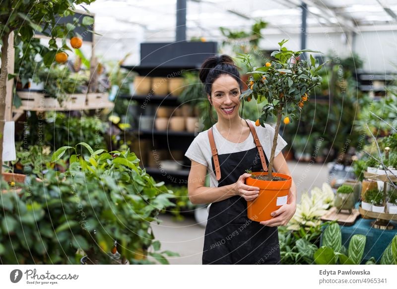 Lächelnde Mitarbeiterin im Gartencenter Gärtnerei Positivität Natur Gartenarbeit kultivieren Wachstum Hobby Frische Pflanze wachsend Flora grün Blumen