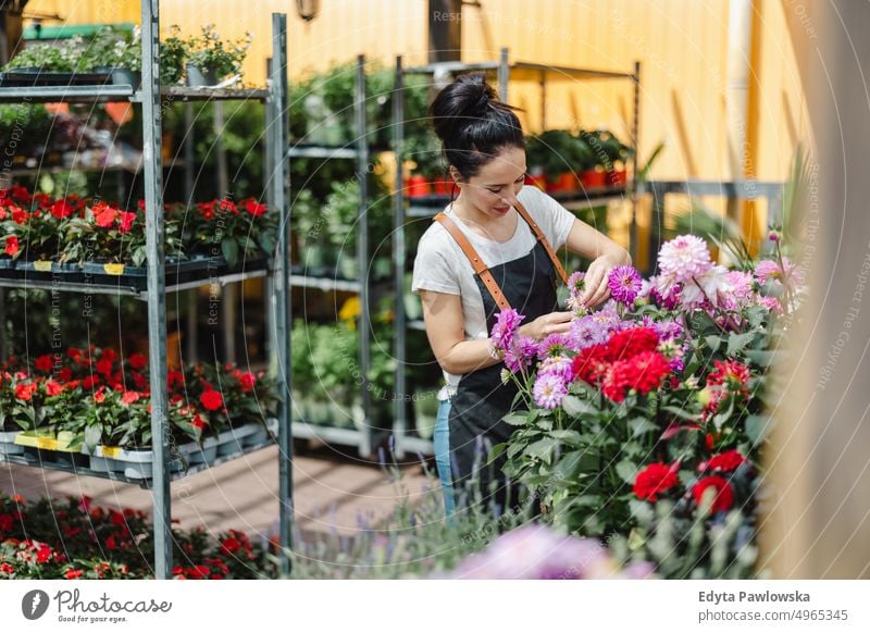 Aufnahme einer jungen Frau bei der Arbeit mit Pflanzen in einem Gartencenter Gärtnerei Lächeln Positivität Natur Gartenarbeit kultivieren Wachstum Hobby Frische