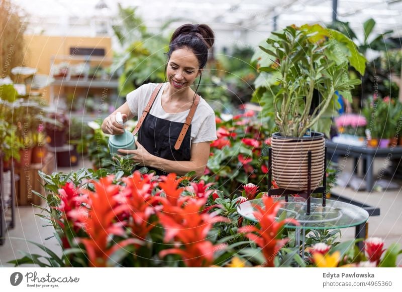 Aufnahme einer jungen Frau bei der Arbeit mit Pflanzen in einem Gartencenter Gärtnerei Lächeln Positivität Natur Gartenarbeit kultivieren Wachstum Hobby Frische