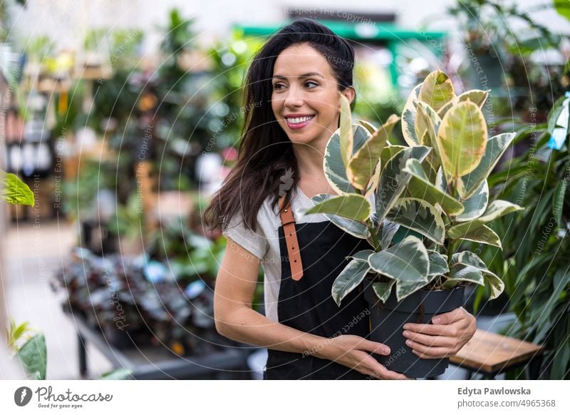 Aufnahme einer jungen Frau bei der Arbeit mit Pflanzen in einem Gartencenter Gärtnerei Lächeln Positivität Natur Gartenarbeit kultivieren Wachstum Hobby Frische