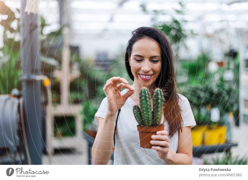 Junge Frau beim Einkaufen im Gartencenter Gärtnerei Lächeln Positivität Natur Gartenarbeit kultivieren Wachstum Hobby Frische Pflanze wachsend Flora grün Blumen