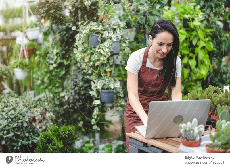 Verkaufsassistentin im Gartencenter mit Laptop Gärtnerei Lächeln Positivität Natur Gartenarbeit kultivieren Wachstum Hobby Frische Pflanze wachsend Flora grün