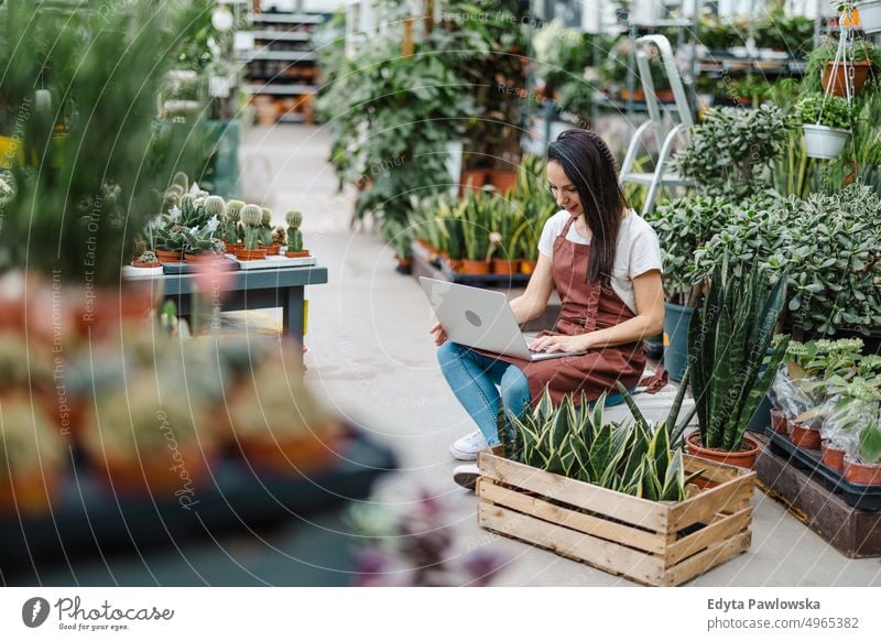 Verkaufsassistentin im Gartencenter mit Laptop Gärtnerei Lächeln Positivität Natur Gartenarbeit kultivieren Wachstum Hobby Frische Pflanze wachsend Flora grün