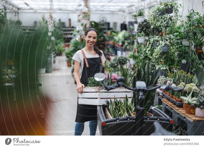 Frau arbeitet in einem Gartencenter Gärtnerei Lächeln Positivität Natur Gartenarbeit kultivieren Wachstum Hobby Frische Pflanze wachsend Flora grün Blumen