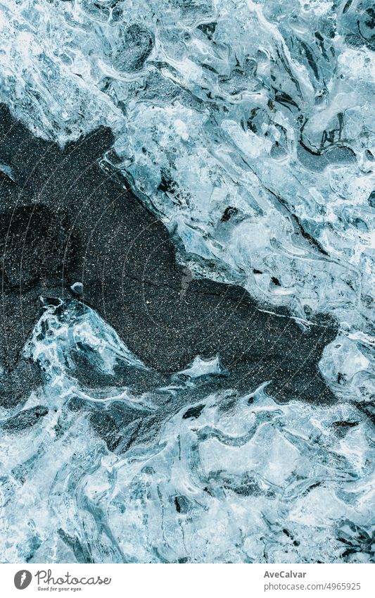 Natürliche zerkratzte Eis gefrorene Oberfläche Design als Textur oder Hintergrund mit schwarzem Sand.wallpaper mit Kopie Raum. Eisblöcke aus am Jökulsárlón Gletscher Lagune, Vatnajökull National Park