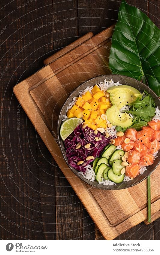 Leckere Poke-Bowl mit verschiedenen Gemüsesorten, Reis und Lachs stoßen Avocado Mango Asiatische Küche Essstäbchen gesunde Ernährung Salatgurke Speise Fisch