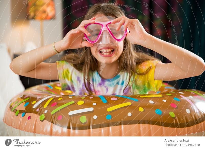 Niedliches Kind mit aufblasbarem Schwimmring und Tauchmaske auf dem Bett im Hotelzimmer sitzend. Spielend, lachend, lächelnd. Glückliche Familie Urlaub. Strand