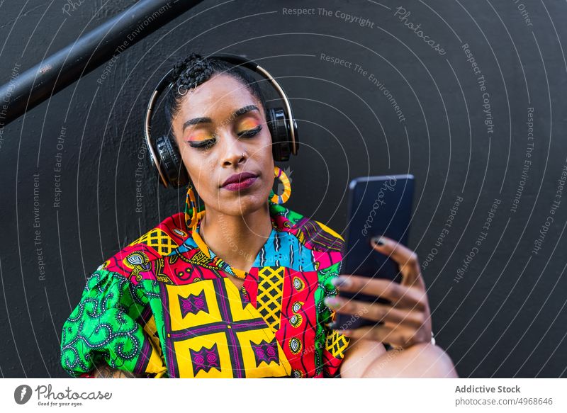 Ethnische Frau benutzt Smartphone auf einer Treppe benutzend Straße Schritt zuhören Musik soziale Netzwerke meloman Stil jung ethnisch Streetstyle urban