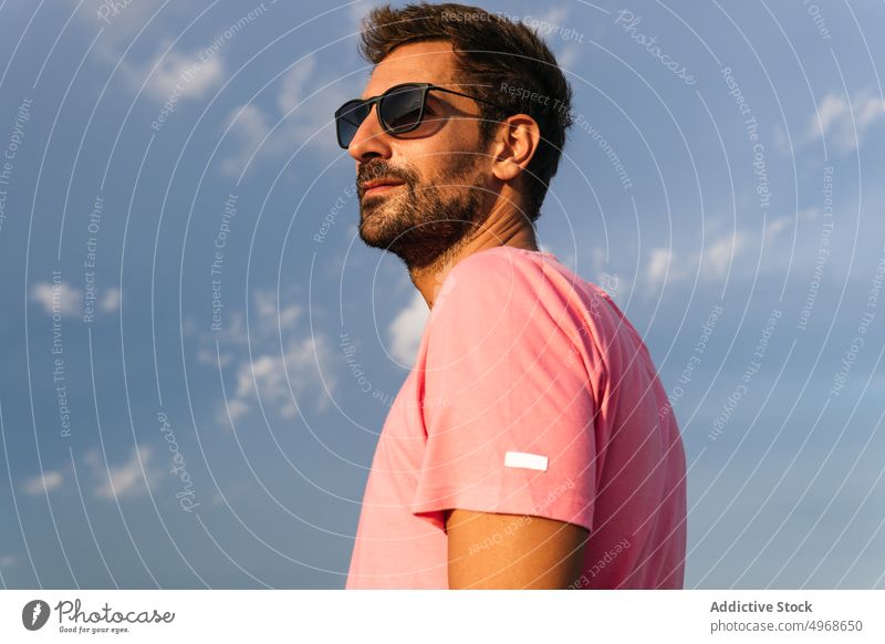 Hispanischer Mann vor blauem Himmel Stil Sommer Blauer Himmel Vorschein Sonnenbrille T-Shirt wolkig Wochenende tagsüber männlich hispanisch ethnisch Erwachsener