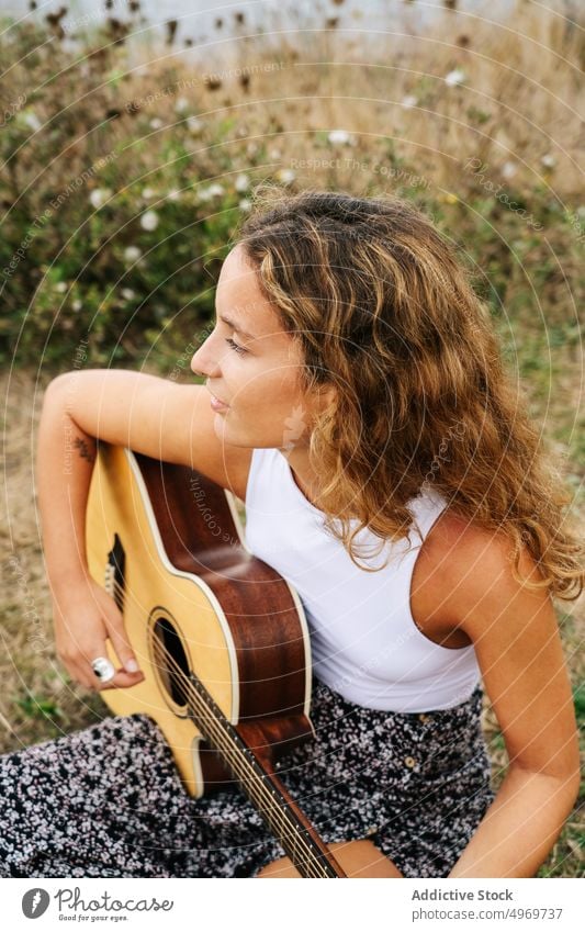 Frau spielt Gitarre in einem Feld mit trockener Vegetation Musik Spielen romantisch jung spielen Instrument heiter Musical Spaß Urlaub Mode Feiertag lässig