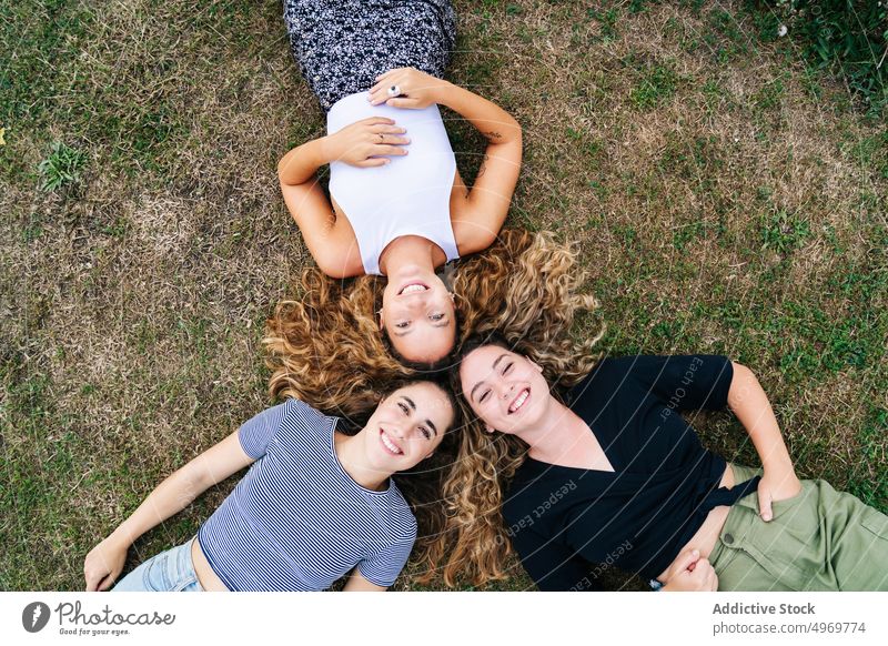 Entspannte Freundin im Gras liegend mit Köpfen im Kreis und lachen Frauen Park Freunde Lügen Rasen Glück Freundschaft Lächeln Zusammensein heiter attraktiv Spaß