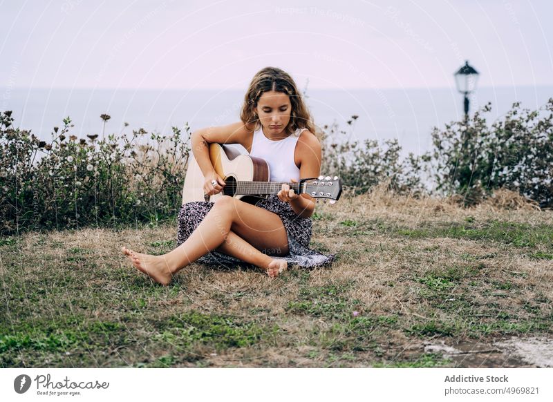 Frau spielt Gitarre in einem Feld mit trockener Vegetation Musik Spielen romantisch jung spielen Instrument heiter Musical Spaß Urlaub Mode Feiertag lässig