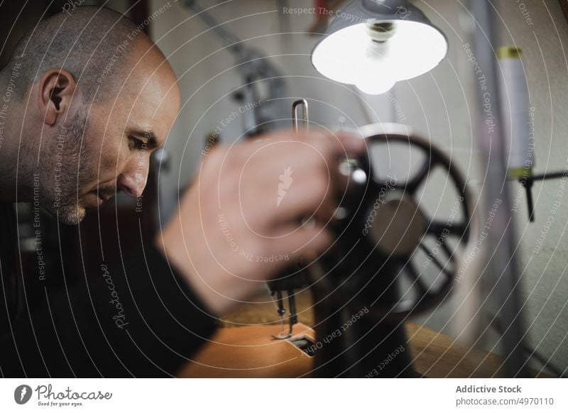 Mann beim Nähen von Textilien im Atelier Schneider Werkstatt Näherei Nähmaschine Hand Arbeitsplatz Mode Bekleidung Damenschneiderin Design Handwerk Gewebe