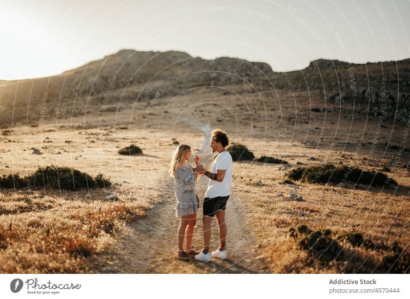 Paar, das sich an den Händen hält, während es auf einem Fußweg gegen einen felsigen Hügel am Abend steht Spaziergang romantisch schlendern Liebe ernst Freundin