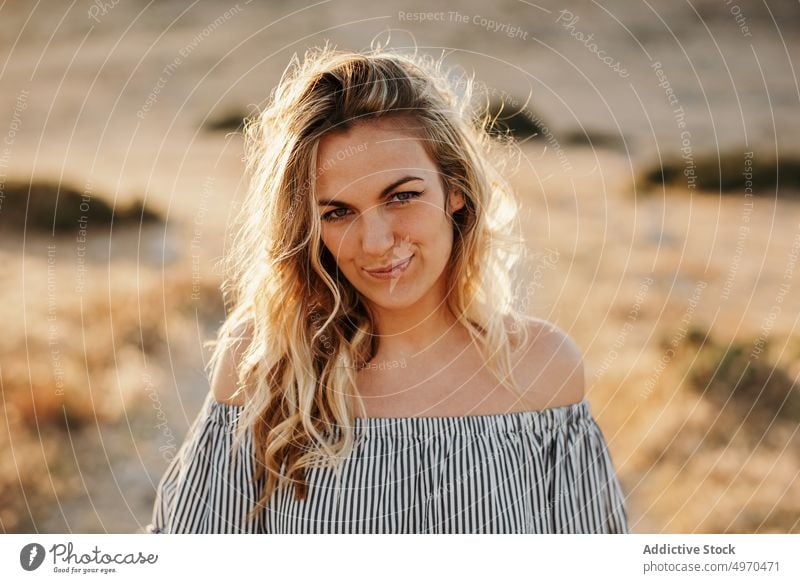 Glückliche junge Frau auf einem Fußweg in der Natur Straße Lächeln Kleid blond Weg trendy Freude zufrieden charismatisch schlank schlanke passen lässig