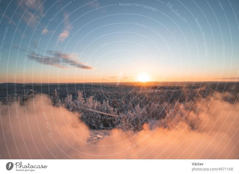 Atemberaubend frostiger Morgen an einem Aussichtspunkt in Rovaniemi, einer finnischen Stadt am Polarkreis. Ein Blick auf die verschneite Landschaft zur goldenen Stunde. Schneebedeckter, unberührter Wald