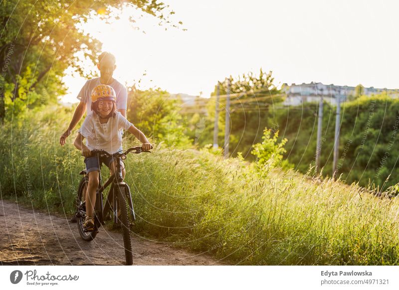 Vater bringt seinem Sohn das Fahrradfahren bei Tag Gesunder Lebensstil aktiver Lebensstil im Freien Spaß Freude Radfahren Aktivität Radfahrer genießend