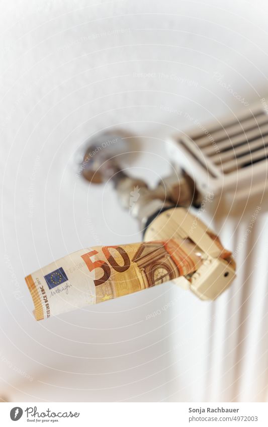 Ein Fünfzigeuroschein steckt in einem Thermostat an einem Heizkörper Geld thermostat Geldscheine heizkosten Heizung Energie Wärme kalt Winter Temperatur weiß