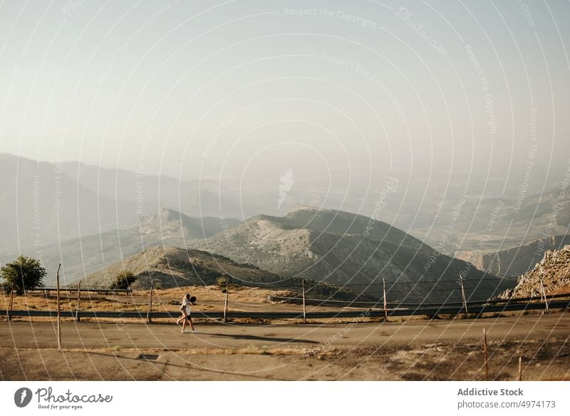 Glückliches Paar umarmt auf der Straße gegen neblige Berge am Horizont Berge u. Gebirge Umarmung Hochland Nebel Abenteuer reisen Ambitus Ausflug Umarmen