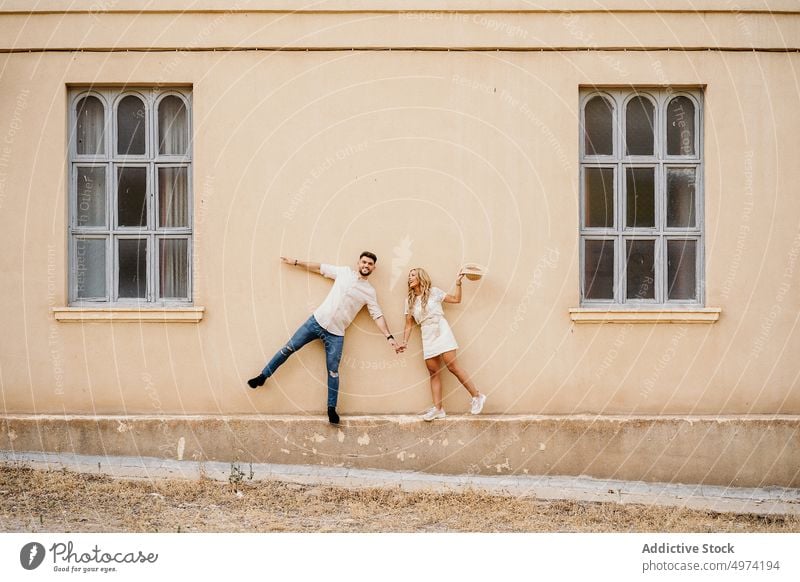 Glückliches junges Paar hat Spaß auf der Straße Außenseite Fenster Partnerschaft heiter Fassade Freundin Freude trendy Gebäude Zusammensein urban Lächeln Stadt