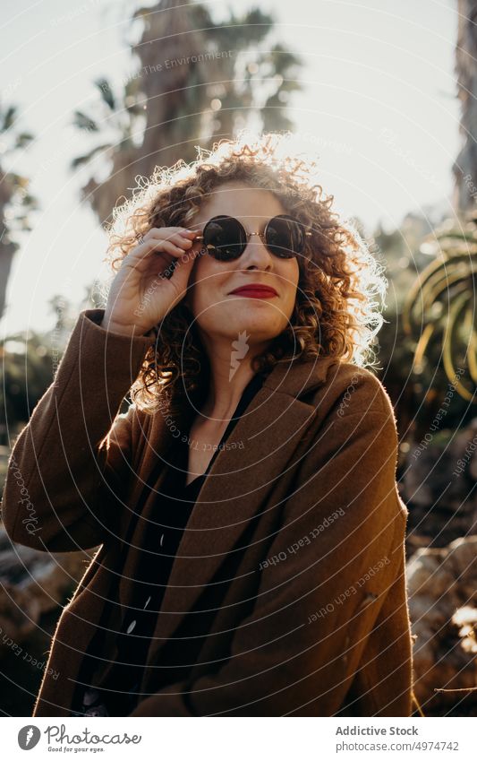 Porträt einer schönen lockigen blonden Frau mit einer schwarzen Sonnenbrille Mode Model fallen Accessoire Bekleidung heiter Mantel selbstbewusst niedlich