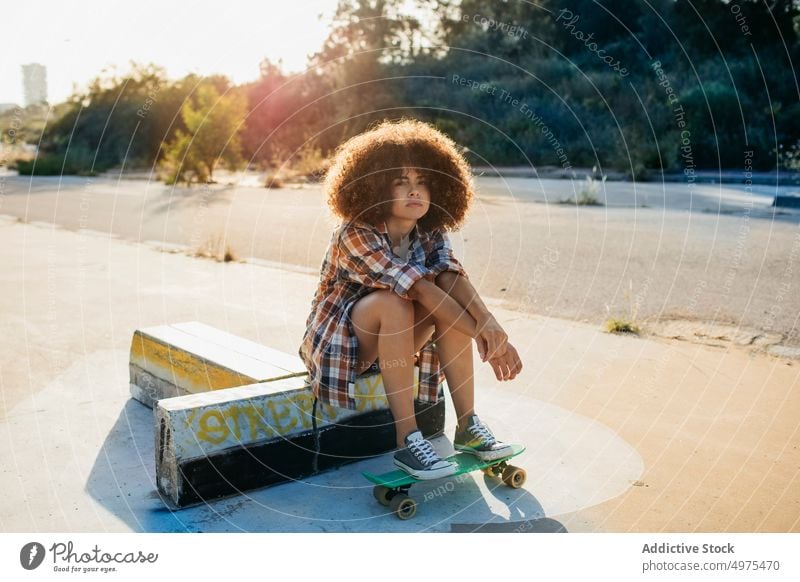 Ruhige afroamerikanische Frau mit Penny Board auf der Straße Lochrasterplatte Sommer Skater cool tausendjährig Afro-Look trendy ruhig Hipster sonnig ethnisch