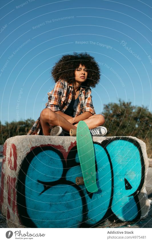 Ruhige afroamerikanische Frau mit Penny Board auf der Straße Lochrasterplatte Sommer Skater cool tausendjährig Afro-Look trendy ruhig Hipster sonnig ethnisch