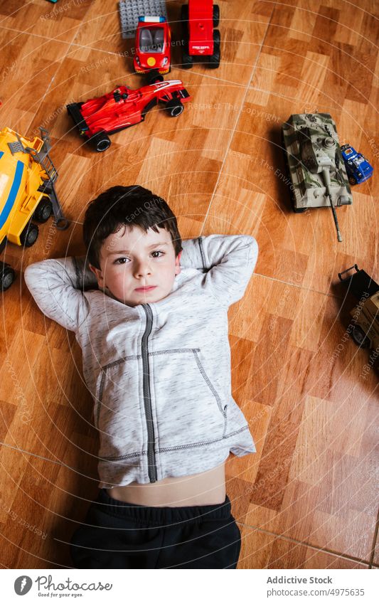 Trauriger Junge spielt mit Spielzeugautos Kind spielen PKW Fahrzeug Stock wenig Lügen männlich Kindheit spielerisch unterhalten heimwärts sorgenfrei Freizeit