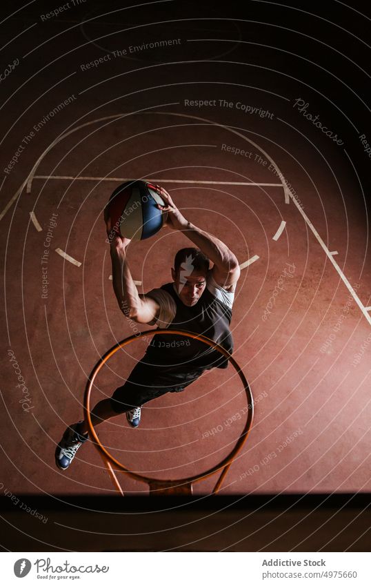 Starker entschlossener Mann, der nachts auf dem Platz Basketball spielt eintauchen Korb Nacht Park Ball springen Schuss Reifen werfen Sportpark Gericht Spiel