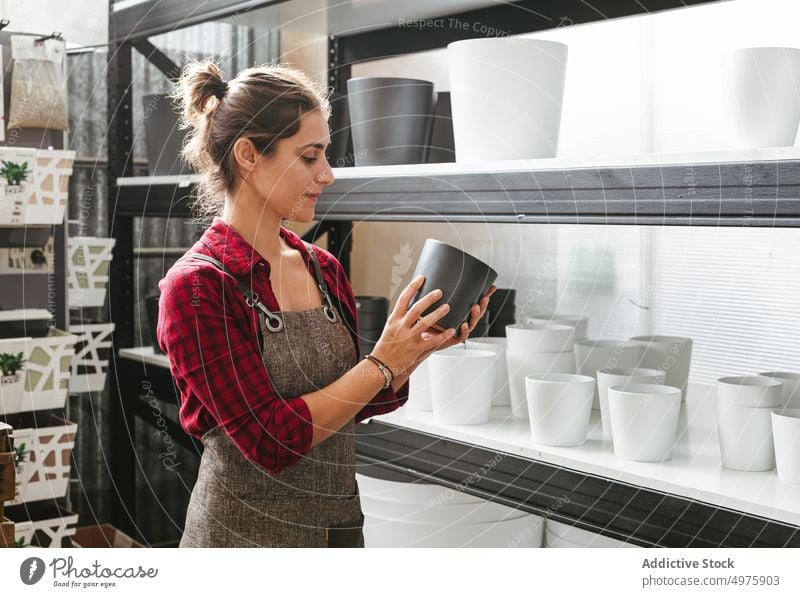 Blumenhändlerin arrangiert Töpfe im Geschäft Laden Arbeit Frau Topf einrichten Regal Beruf Lager Verkäufer Schürze Kleinunternehmen Werkstatt Job Container