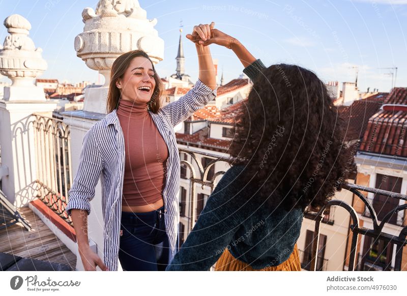 Fröhliche, vielfältige Frauen tanzen auf dem Dach Tanzen Händchenhalten Freund aufgeregt heiter Dachterrasse Terrasse freudig Spaß haben sorgenfrei lässig Glück