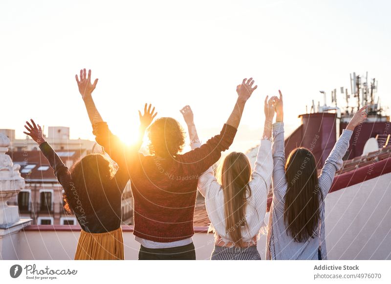 Gruppe von nicht erkennbaren Freunden, die auf einer Terrasse feiern und das Stadtbild beobachten Dachterrasse Sonnenuntergang bewundern Zusammensein