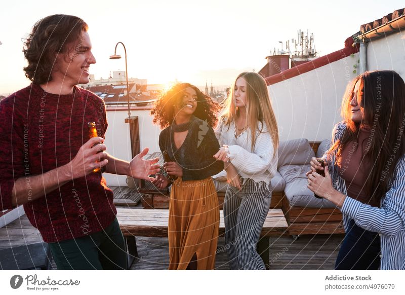 Fröhliche, bunt gemischte Freunde tanzen und genießen Bier auf dem Dach Tanzen Dachterrasse Party Schnaps Glück Zusammensein Sonnenuntergang Treffpunkt aktiv