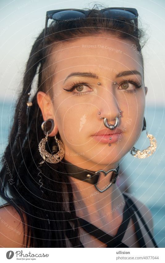 Porträt einer sensiblen jungen Teenagerin, Mädchen mit dunklem Haar, Dreadlocks, vielen Piercings Rastalocken sensibel Frau dunkel Behaarung Gesicht Sommer