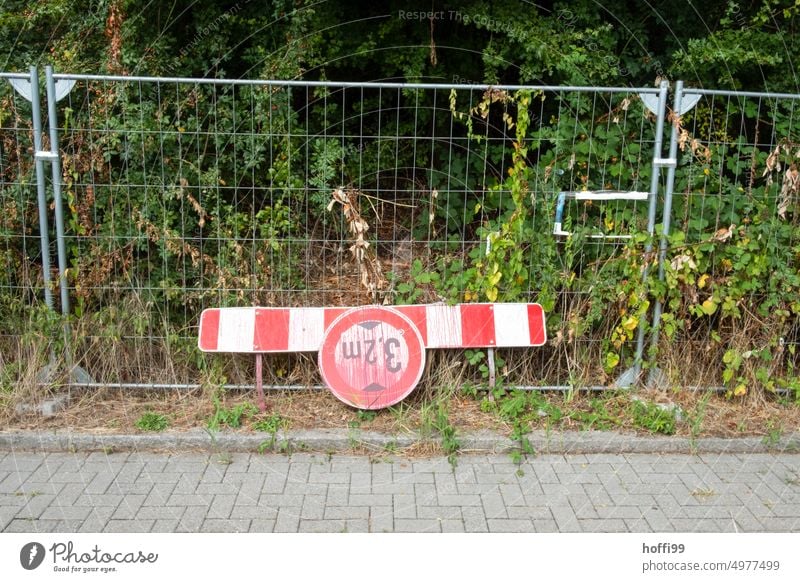 rot besprühtes Warnschild zur Durchfahrtshöhe auf Barke vor Bauzaun und Gebüsch. - urbanes Stilleben höhenbegrenzung verkehrszeichen durchfahrtshöhe maximalhöhe