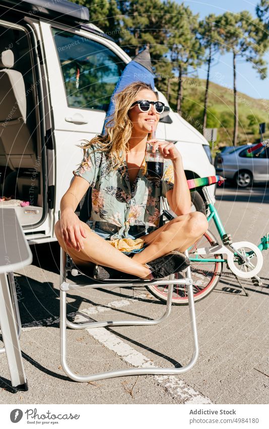 Fröhliche Frau, die einen Saft genießt, während sie im Wohnwagen auf dem Campingplatz sitzt Reise Ausflug Transport Urlaub Abenteuer reisen Sommer Wohnmobil