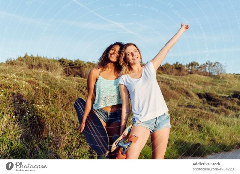 Freundinnen gehen mit Skateboards die Straße entlang Frauen Porträt Skater Landschaft Spaß schön jung Holzplatte trendy stylisch Skateboarderin Lifestyle