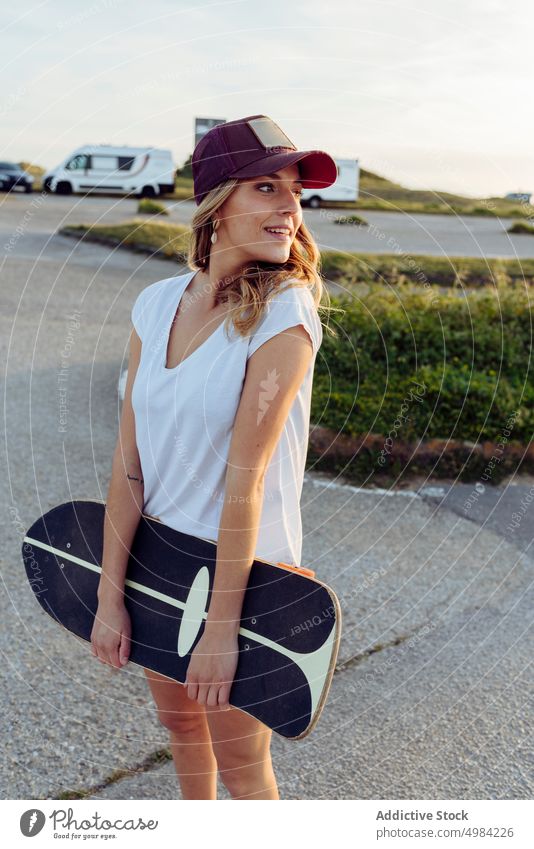 Skater, der im Freien wegschaut und ein Skateboard hält Frau Mode eine Kaukasier Skateboarderin Lifestyle cool Mädchen urban Straße Skateboarding Freizeit