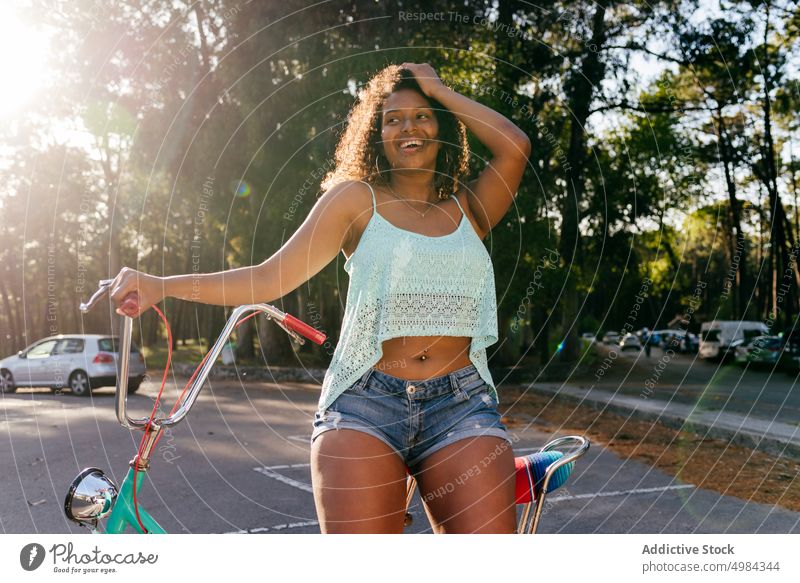 Frau lächelt und schaut weg, während sie auf einem Fahrrad sitzt Sommer Glück Person Lächeln jung hübsch Ethnizität Afrikanisch Lifestyle Porträt ethnisch Park