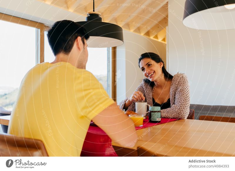 Junges Paar beim Frühstück am Tisch habend Tasse Stuhl Fenster hispanisch Raum Frau Mann Becher Saft trinken Lächeln jung schön Glück Gericht Sitzen attraktiv