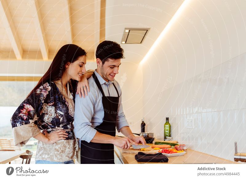 Seitenansicht eines attraktiven Paares beim Kochen Vorbereitung Küche Gemüse hispanisch Schürze Schneiden Schneidebrett Tisch Frau Mann jung Abendessen