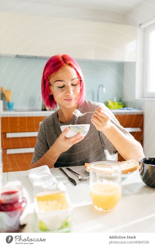 Junge Frau beim gesunden Frühstück zu Hause Gesundheit Morgen heimwärts Lächeln Tisch gemütlich essen Küche Appartement modern jung rosa Haare gefärbtes Haar