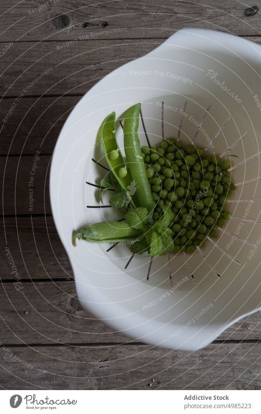 Schüssel mit Erbsen und Minze abtropfen lassen Schalen & Schüsseln Hülsen frisch grün Blätter rustikal Ackerbau Wachstum Pflanze reif organisch Snack Samen